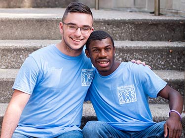 Male buddy pair sitting on stairs with arms over one another's shoulders