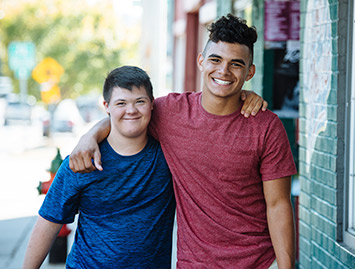 Two male Best Buddies participants walking together with smiles on their faces