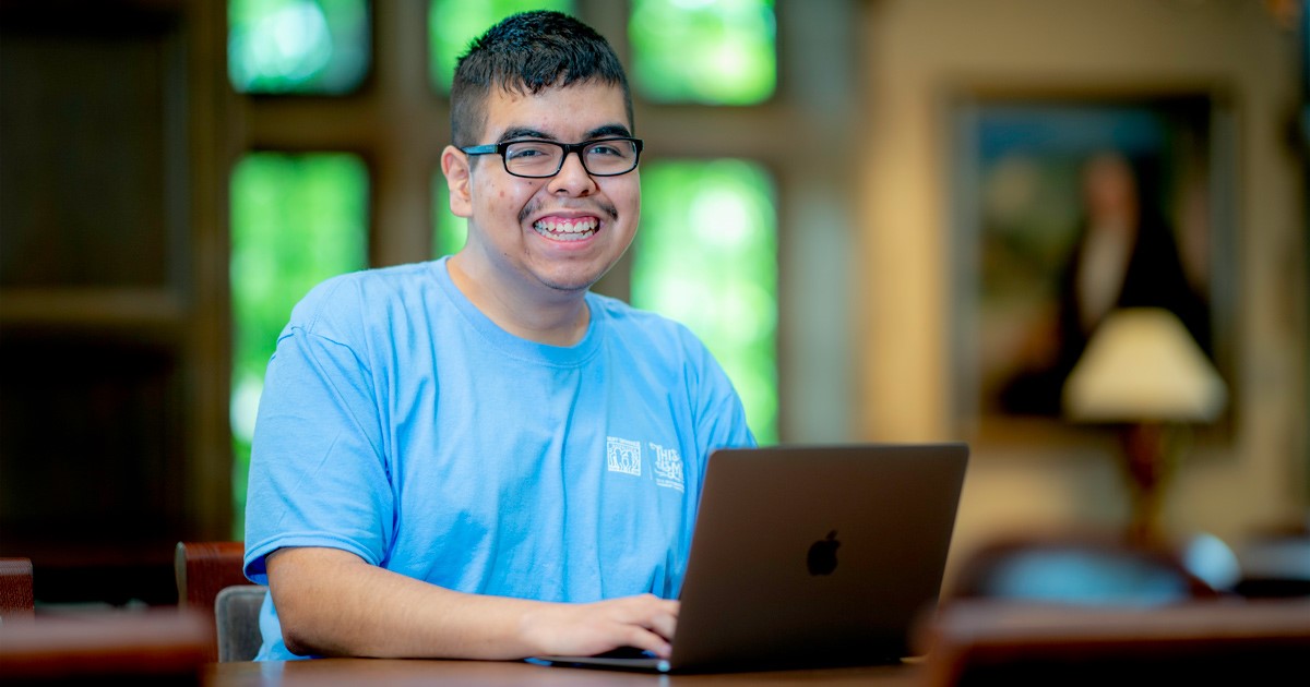 young man smiling using a laptop