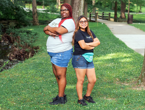 Best Buddies female Friendship pair smiling while standing next to each other in an open field