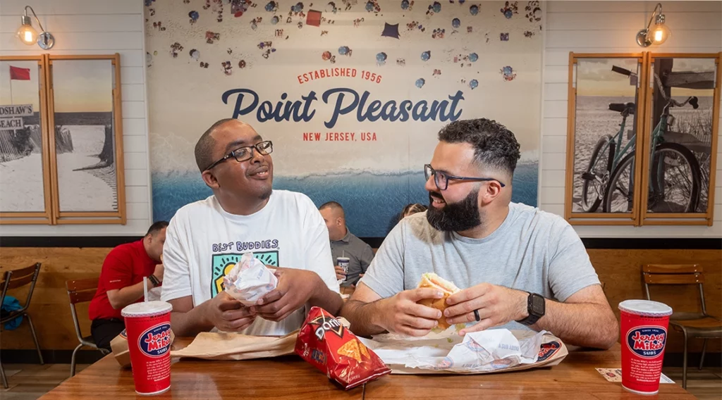 Two Best Buddies participants eating Jersey Mike's subs.