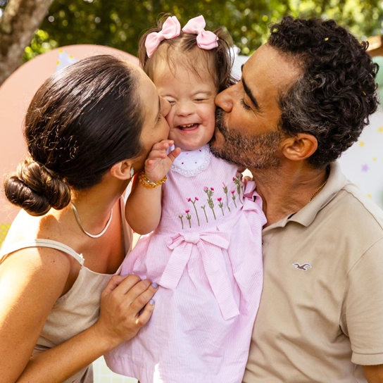 Parents kissing child with IDD