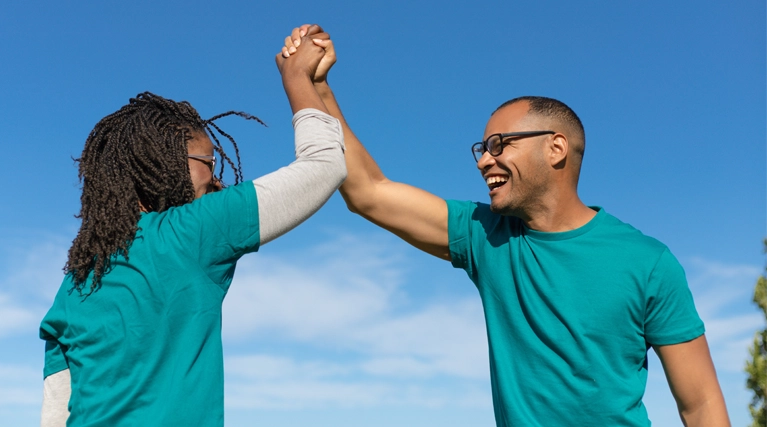 Two men smiling and high-fiving outside.